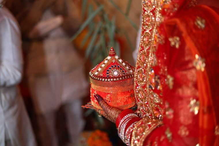 A red sindoor box held by a bride