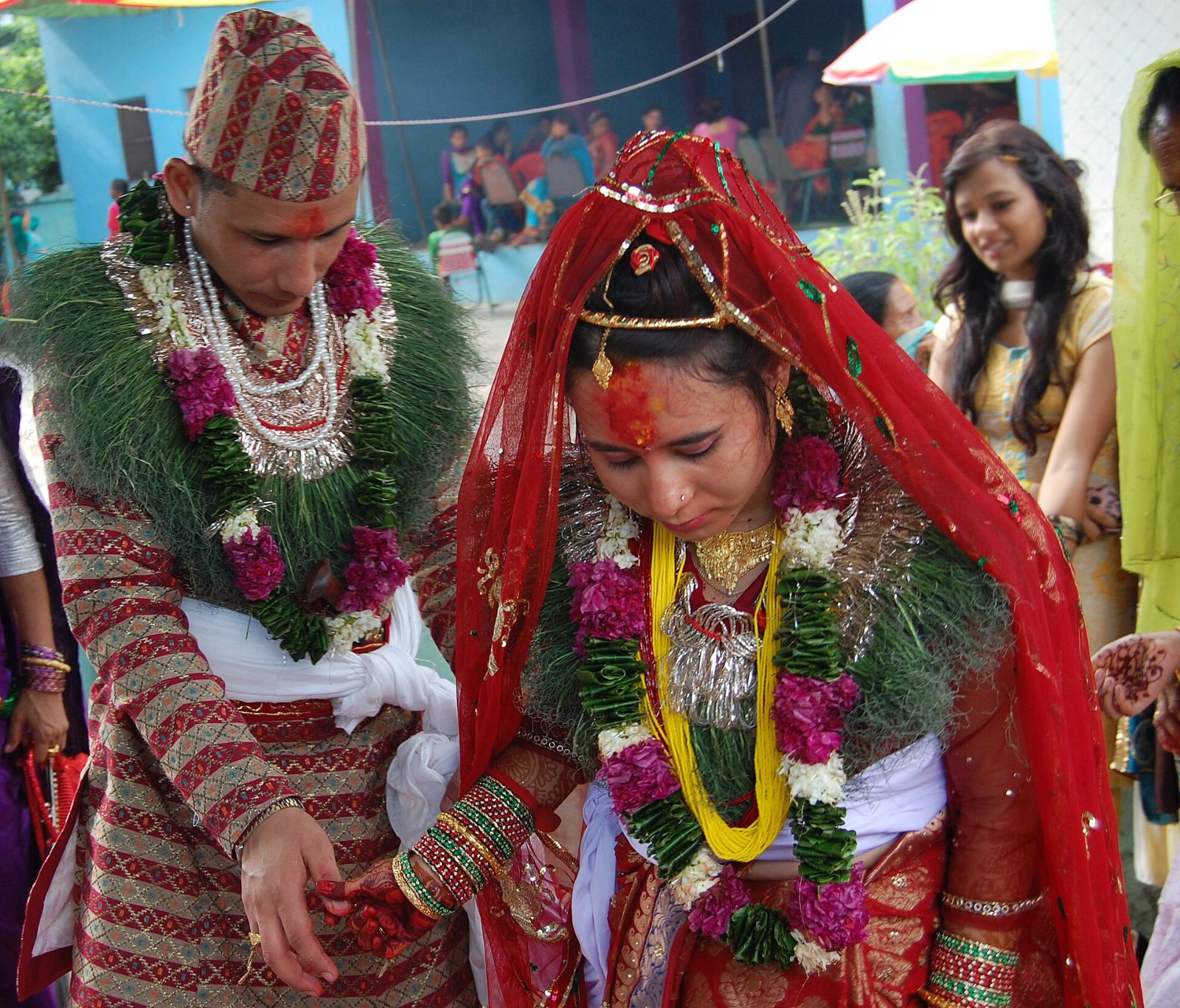 A Nepali bride and groom in red and gold, with garlands, during their wedding