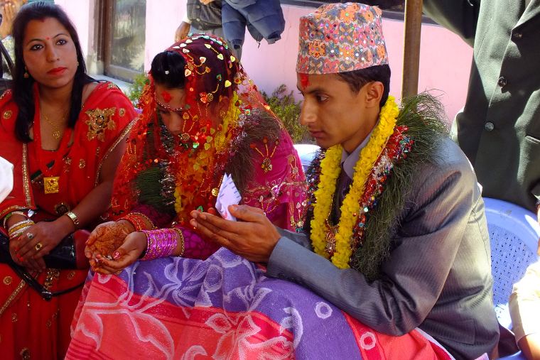 A bride and groom during their wedding ritual, surrounded by family